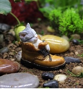 Macro detail of a resin sleeping kitten inside a brown boot for succulent gardens