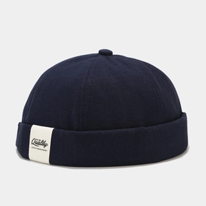 Detail of navy blue canvas sailor cap showing the top button and quality fabric label