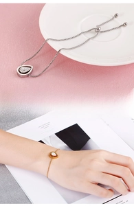 Detail of adjustable stainless steel bracelets with pavé pear drop charms in silver and gold