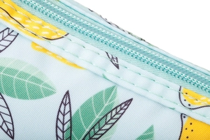 Detailed macro view of light blue canvas wash bag with yellow lemon print and blue zipper