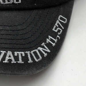 Close-up of high-quality white embroidery and stitching on a washed canvas baseball cap