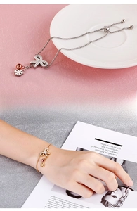Detail of adjustable butterfly bracelet with snowflake and bell charms in gold and silver
