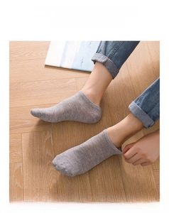 Close-up of grey knit low-cut invisible liner socks worn on model on wooden floor