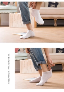Detail of white low-cut disposable socks showing knit texture on a wooden floor