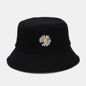 Détail d'un bob en coton noir avec broderie de marguerite blanche sur le devant du chapeau