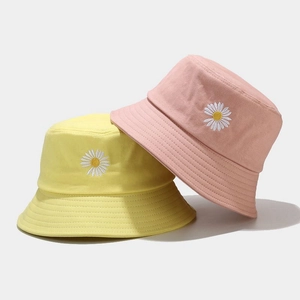 Détail des chapeaux bob en coton rose et jaune avec broderie de marguerites