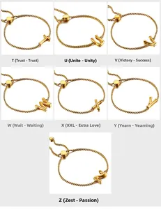 Detail of gold snake chain bracelets with bamboo style letter charms T to Z and ball slider