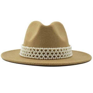 Détail du chapeau fedora en laine camel avec un ruban décoratif élégant en perles blanches