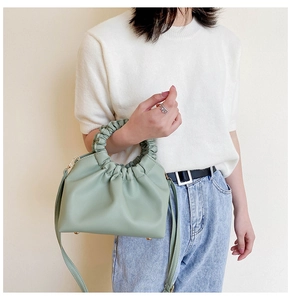 Detail of mint green ruched cloud bag showing gathered handle and metallic rivets