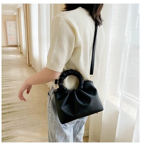 Detail of a chic black scrunchie handle bag with gold hardware and shoulder strap