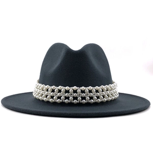 Close-up of a wide-brim black fedora featuring a woven pearl decorative band and flat brim