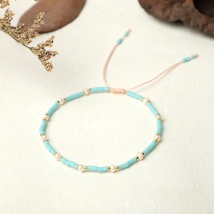 Close-up of handmade blue seed bead bracelet with pearls and adjustable woven cord