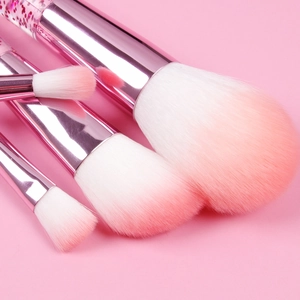 Detail of pink liquid glitter makeup brushes with gradient bristles and metallic handles