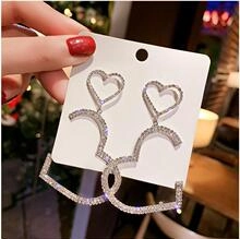 Dettaglio macro di una spilla a cuore e doppia C color argento con strass scintillanti