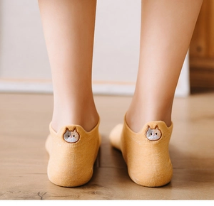 Close-up of yellow low-cut socks with cute cat embroidery on the heel on wood floor