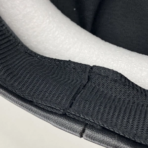 Detailed close-up showing black fabric edge stitching and foam padding of the baker boy hat