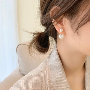 Detail of silver needle earrings featuring heart-shaped pearl drop and round pearl top