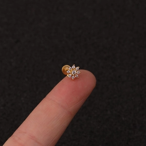 Golden flower zircon stud for lip or cartilage with flat back, shown on a fingertip