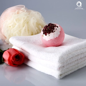Détail d'une boule de bain rose avec des pétales séchés sur une serviette blanche