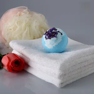 Gros plan d'une bombe de bain bleu clair avec fleurs séchées violettes sur serviette blanche