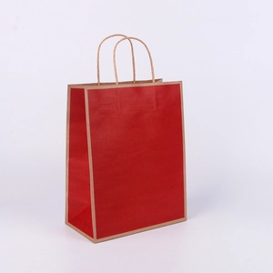 Detail of a red kraft paper shopping bag with brown twisted handles on a white background