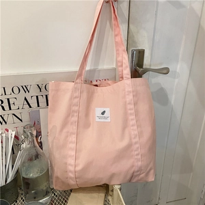 Detailed close-up of a pink canvas tote bag with a white fabric patch on a door handle