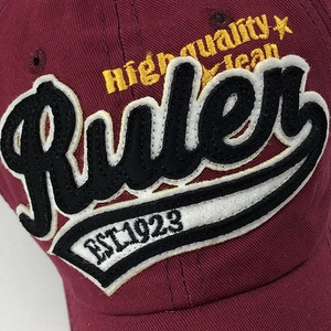 Detailed close-up of high-quality towel embroidery and 1923 text on burgundy cotton cap