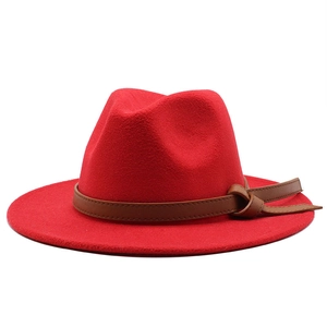 Close-up of a red wool fedora hat with a decorative brown leather band and knot detail