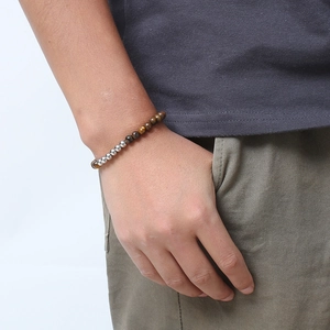 Minimalist tiger eye stone beaded bracelet with polished steel spheres on a model's wrist