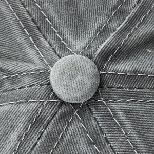 Macro shot of the top button and reinforced stitching on a vintage washed cotton baseball cap