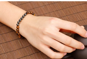 Tiger eye and hematite beaded bracelet worn on wrist with traditional tea set background