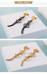 Détail de boucles d'oreilles géométriques avec de longs glands en métal doré et noir