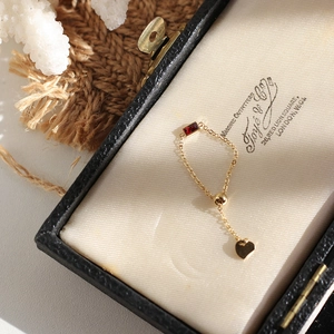 Adjustable gold chain ring with emerald cut red gemstone and heart charm detail