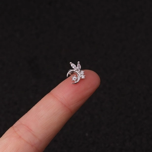 Macro shot of silver crescent and star stud earring with clear zircons on a fingertip