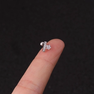 Detailed close-up of a 16G silver stainless steel ear stud with star-shaped zircon on a finger
