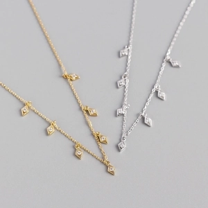 Macro shot of silver and gold diamond-shaped necklace pendants with cubic zirconia inlay