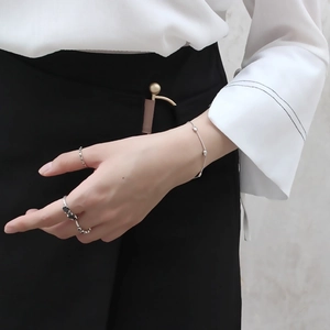 Close-up of minimalist S925 sterling silver beaded bracelet and rings on a model