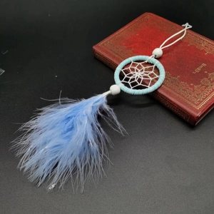 Handmade light blue dreamcatcher with white feathers on a vintage book backdrop