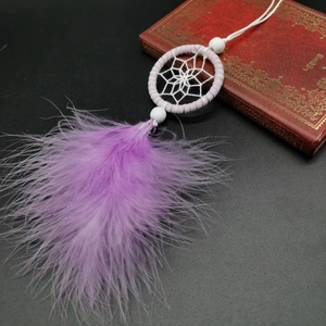 Pink and purple dreamcatcher bag charm with soft feathers and beads on a vintage book