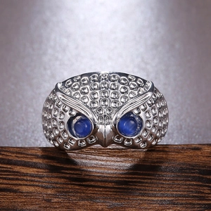 Macro view of vintage silver owl ring with detailed feather texture and blue stone eyes