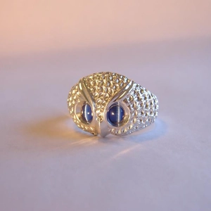 Macro detail of owl ring featuring blue cat eye stone eyes and fine feather textures