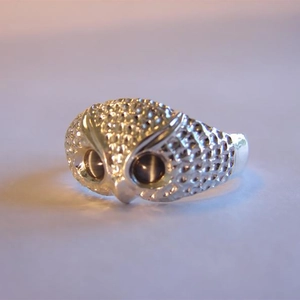 Macro shot of owl head ring showing detailed feather texture and dark crystal eyes
