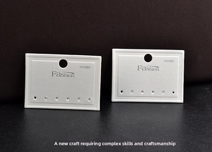 Close-up of white jewelry display cards with Fashion text and six earring hanging holes
