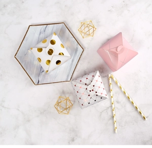 Detail of square gift boxes with gold foil dots and geometric patterns on marble