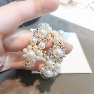 Detailed view of C-shaped earrings with pearls and rhinestones on a gold setting