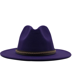 Detail van de donkerpaarse fedora hoed met bruine gevlochten band en wollen textuur