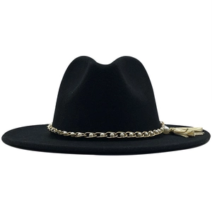 Detail of elegant black wool felt hat with gold chain, pearls and white tassel trim