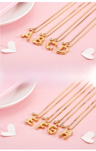 Detailed view of bamboo textured 18K gold alphabet pendants with white rhinestones
