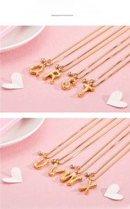 Detailed macro view of gold-plated steel initial pendants from Q to X with small crystals