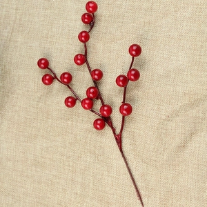 Close-up of festive artificial red berry stems with glossy fruits on burlap background
